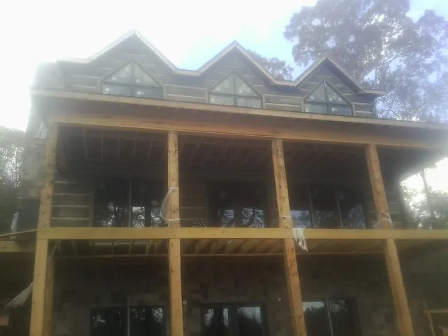 Dormers and porch framing on a large log home under construction — Roof Coating work by our crew in Montevallo
