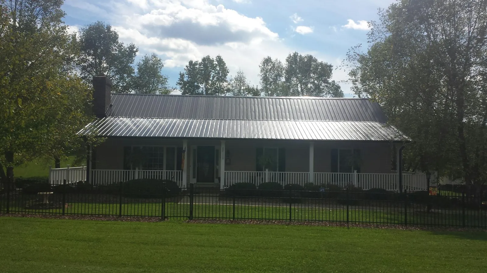 Gray metal roof on a brick ranch with a full width front porch — Gutter Guard Installation work by our crew in Montevallo