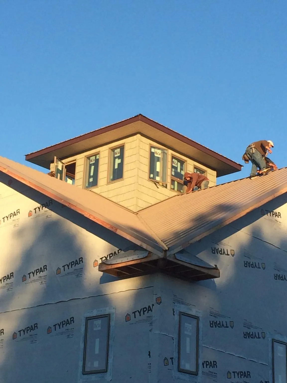 Roofers working around a rooftop cupola on a new metal roof at sunset — Roof Waterproofing in Montevallo by Roofing Brothers